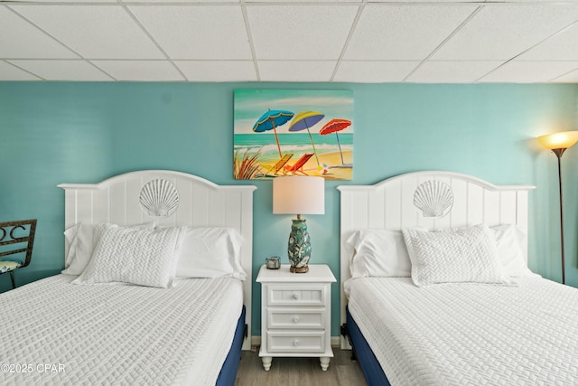 bedroom with a paneled ceiling and wood finished floors