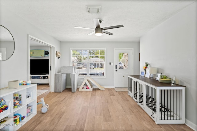 rec room with visible vents, baseboards, a ceiling fan, a textured ceiling, and light wood-style floors