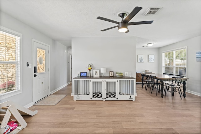 foyer entrance featuring visible vents, light wood-style floors, ceiling fan, a textured ceiling, and baseboards