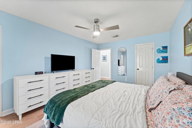 bedroom with a ceiling fan, visible vents, baseboards, and wood finished floors