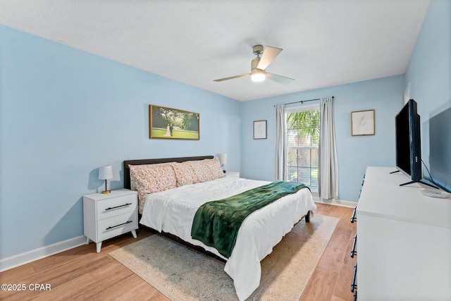 bedroom with ceiling fan, light wood-style flooring, and baseboards