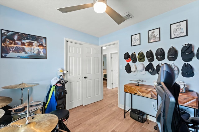 office space featuring a ceiling fan, visible vents, and light wood-style floors