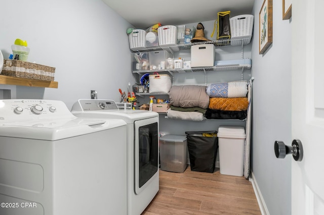 clothes washing area featuring baseboards, laundry area, light wood finished floors, and washer and dryer