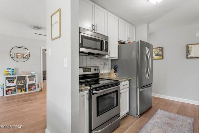 kitchen with visible vents, baseboards, white cabinets, appliances with stainless steel finishes, and light wood finished floors