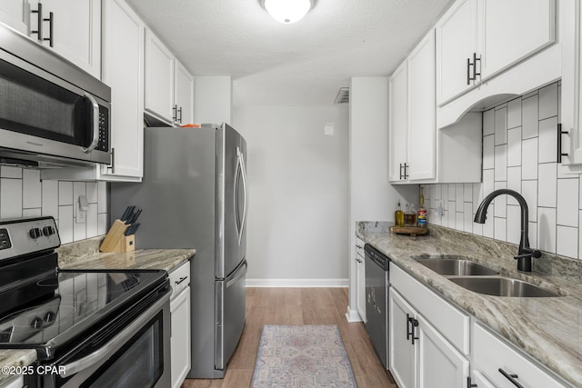 kitchen with stainless steel appliances, white cabinets, a sink, and tasteful backsplash