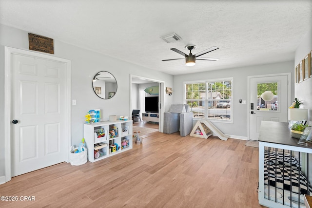 playroom featuring light wood-style flooring, visible vents, and a textured ceiling