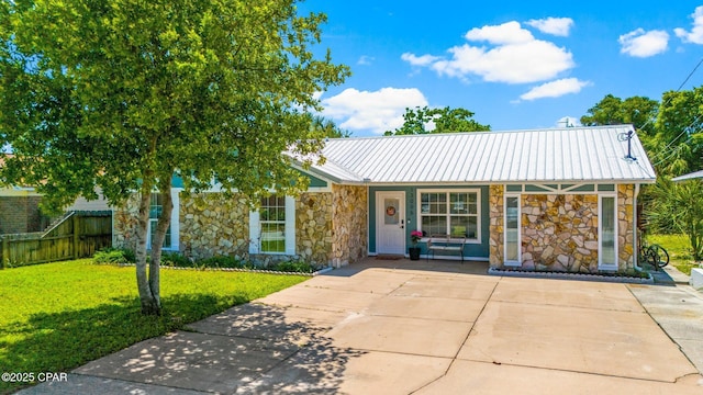 view of front of property with stone siding, fence, metal roof, and a front yard