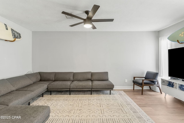 living room with baseboards, a textured ceiling, a ceiling fan, and wood finished floors