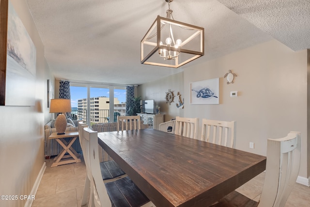 dining area with light tile patterned flooring, a notable chandelier, a textured ceiling, and baseboards