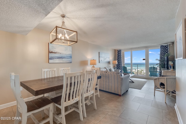 dining space featuring a wall of windows, light tile patterned floors, baseboards, an inviting chandelier, and a water view