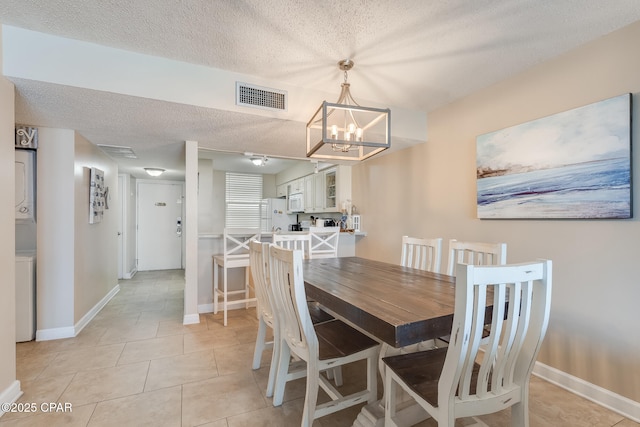 dining room with stacked washer / dryer, baseboards, visible vents, and a textured ceiling