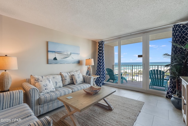 living room with tile patterned floors, floor to ceiling windows, a textured ceiling, and a water view