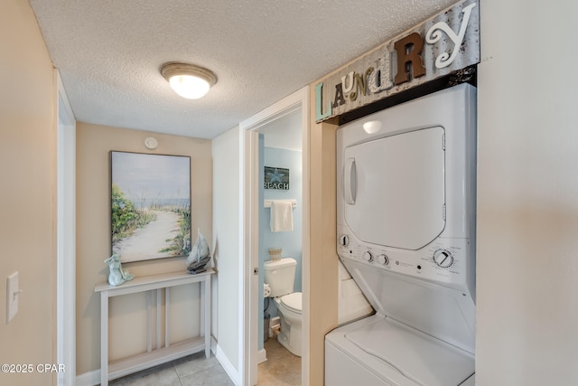 laundry room featuring light tile patterned floors, a textured ceiling, laundry area, and stacked washing maching and dryer