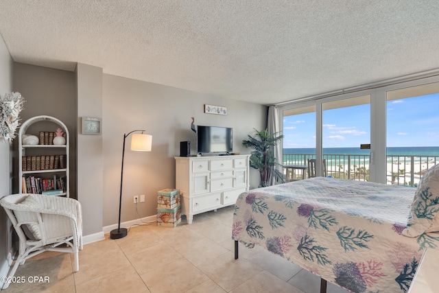 bedroom featuring light tile patterned floors, baseboards, access to exterior, floor to ceiling windows, and a textured ceiling