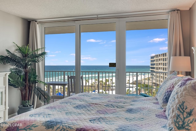 bedroom with access to outside, a textured ceiling, a beach view, and a water view