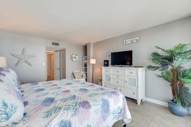 bedroom with light tile patterned floors, visible vents, a textured ceiling, and baseboards