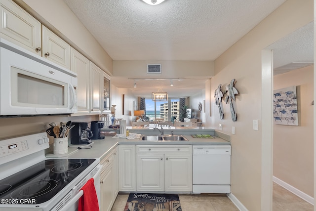 kitchen with visible vents, white cabinets, white appliances, a textured ceiling, and a sink