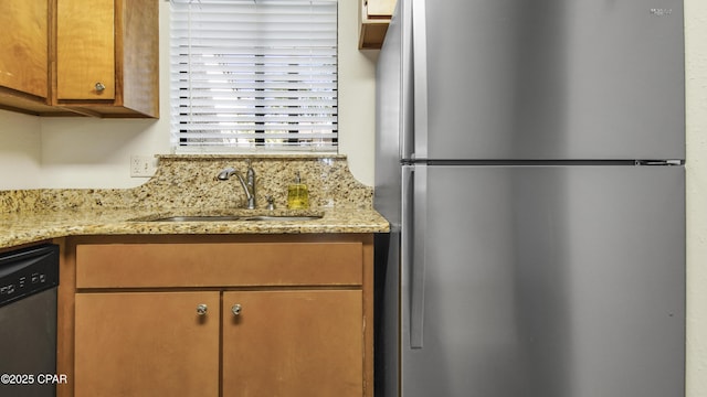 kitchen featuring a sink, light stone counters, brown cabinetry, and stainless steel appliances