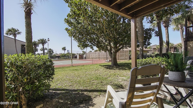 view of yard with a tennis court and fence