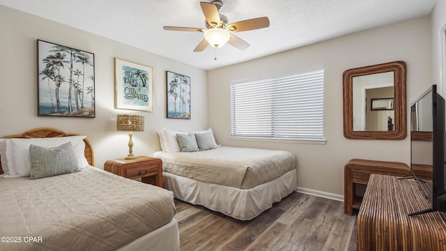 bedroom with a textured ceiling, a ceiling fan, baseboards, and wood finished floors