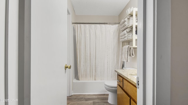 full bathroom with toilet, a textured ceiling, wood finished floors, shower / tub combo, and vanity