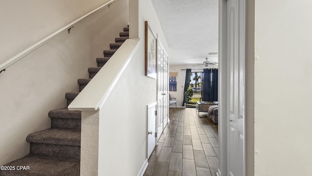 stairs featuring a textured ceiling, ceiling fan, and wood tiled floor