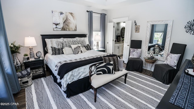 bedroom with connected bathroom and wood finished floors