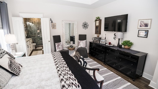 bedroom featuring dark wood-style floors, ensuite bathroom, and baseboards