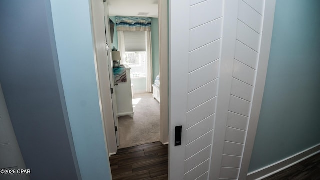 corridor featuring baseboards and dark wood-style flooring