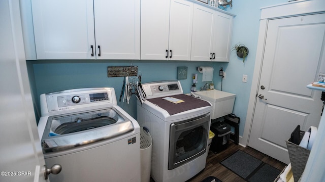 washroom featuring washing machine and clothes dryer, cabinet space, dark wood-type flooring, and a sink