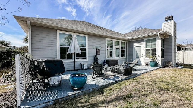 back of house with an outdoor fire pit, a yard, a shingled roof, a chimney, and a patio area