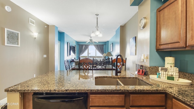 kitchen featuring brown cabinetry, visible vents, dark stone countertops, and a sink