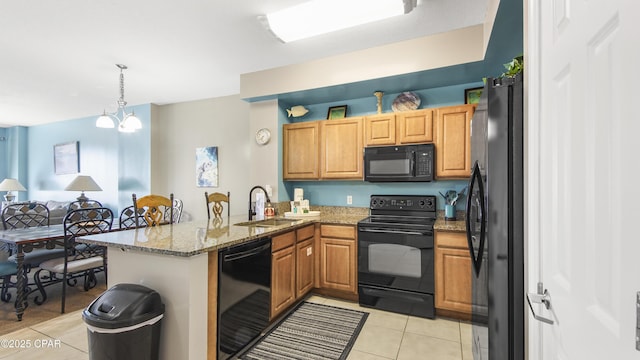 kitchen featuring light tile patterned floors, light stone countertops, a peninsula, a sink, and black appliances