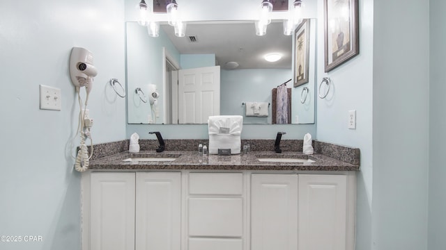 bathroom with double vanity, visible vents, and a sink