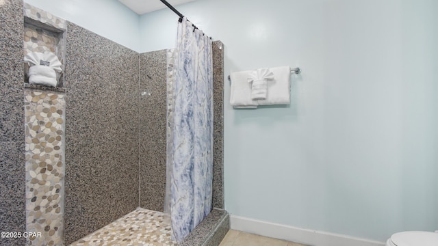 bathroom with baseboards, toilet, a shower stall, and tile patterned flooring