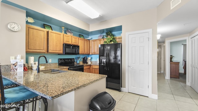 kitchen with light stone counters, visible vents, a peninsula, a sink, and black appliances