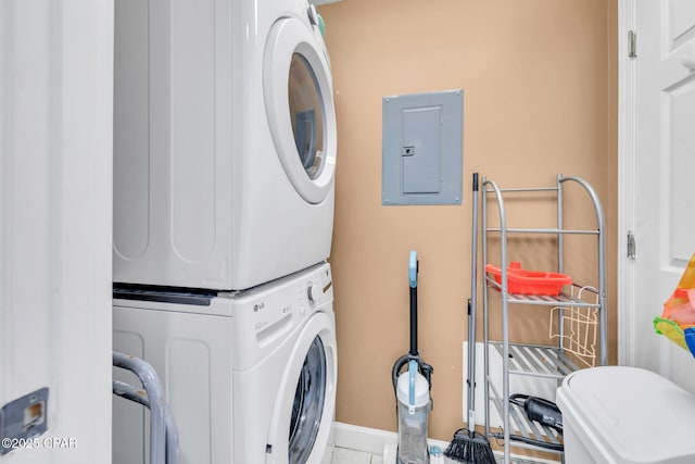 clothes washing area with baseboards, laundry area, stacked washer and clothes dryer, and electric panel