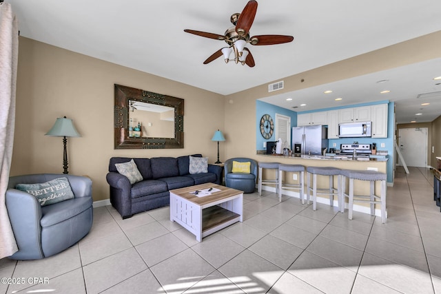 living room with light tile patterned floors, baseboards, visible vents, and ceiling fan