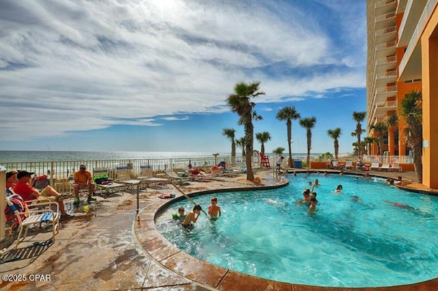 pool with a patio area, fence, and a water view