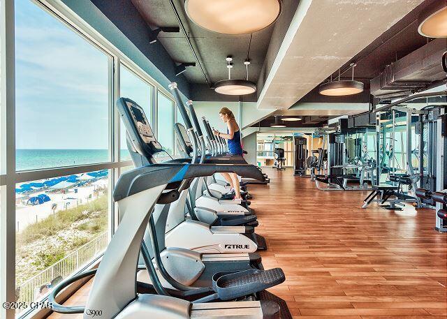 exercise room featuring a water view and wood finished floors