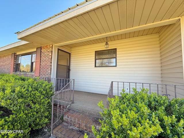 doorway to property featuring covered porch and brick siding