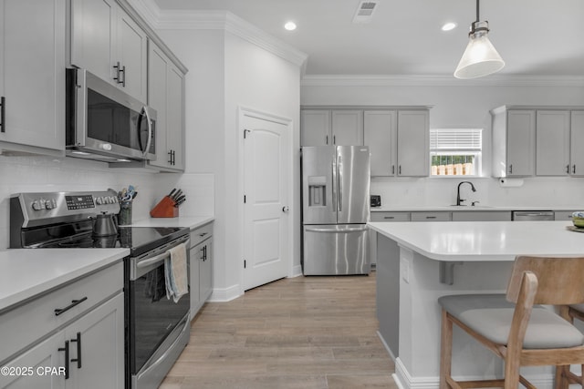 38 Cozy Cv, Freeport, FL 32439 - kitchen with ornamental molding, gray cabinetry, a breakfast bar, visible vents, and appliances with stainless steel finishes