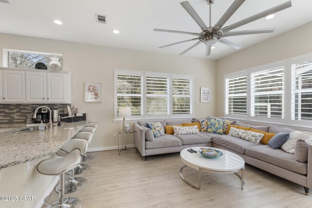 living area with visible vents, baseboards, ceiling fan, light wood-type flooring, and recessed lighting