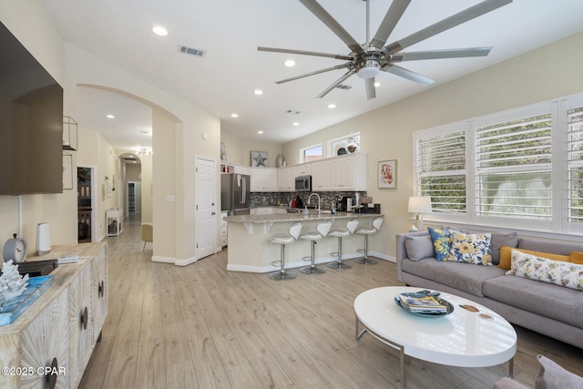 living room featuring light wood finished floors, visible vents, recessed lighting, arched walkways, and a ceiling fan