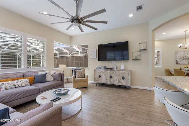 living room with visible vents, light wood finished floors, recessed lighting, arched walkways, and ceiling fan with notable chandelier