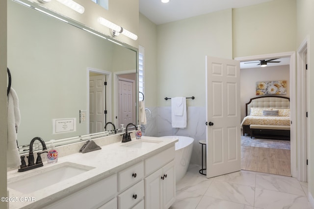 ensuite bathroom with a freestanding tub, connected bathroom, marble finish floor, and a sink