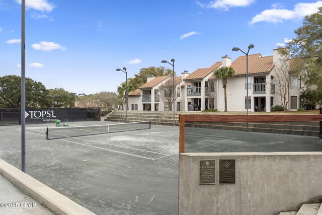 view of tennis court featuring a residential view and fence