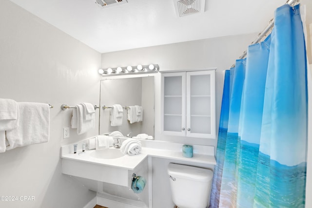 bathroom with a shower with shower curtain, visible vents, a sink, and toilet