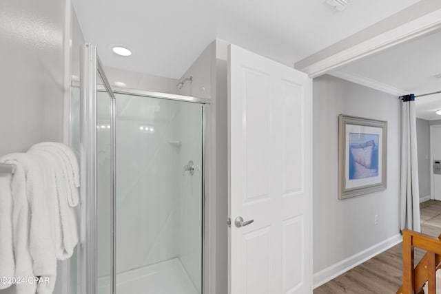 bathroom with ornamental molding, a stall shower, baseboards, and wood finished floors