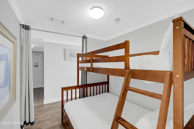 bedroom featuring baseboards, visible vents, crown molding, and wood finished floors